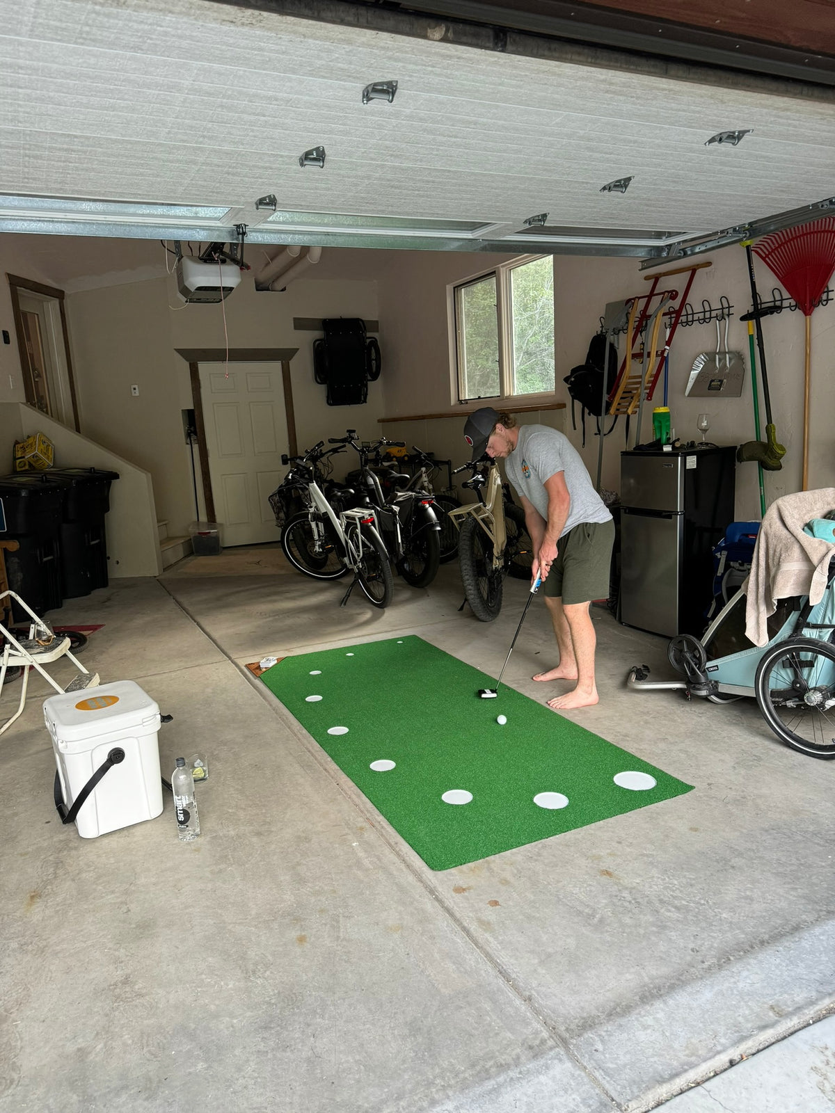 Golfer practicing on a 9Putt Mat in a garage